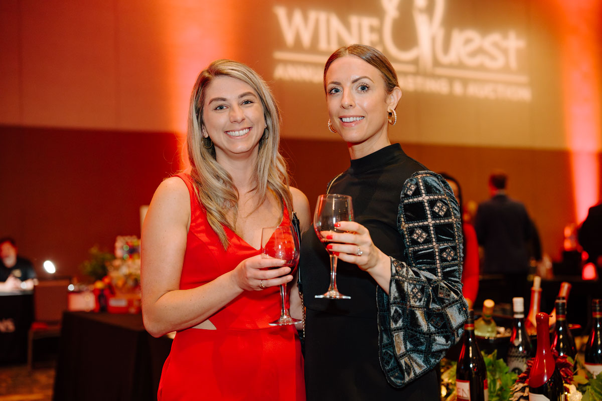 Photo of two women smiling with wine glasses at Wine Quest.