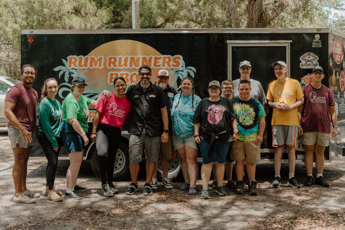 Rum Runners BBQ team poses in front of food truck with staff and guests.