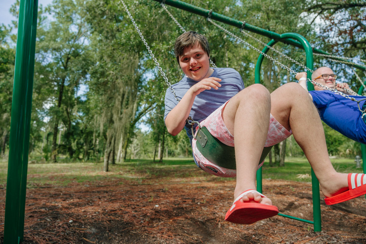 photo of camp guests grinning on the swings during their summer at camp thunderbird.