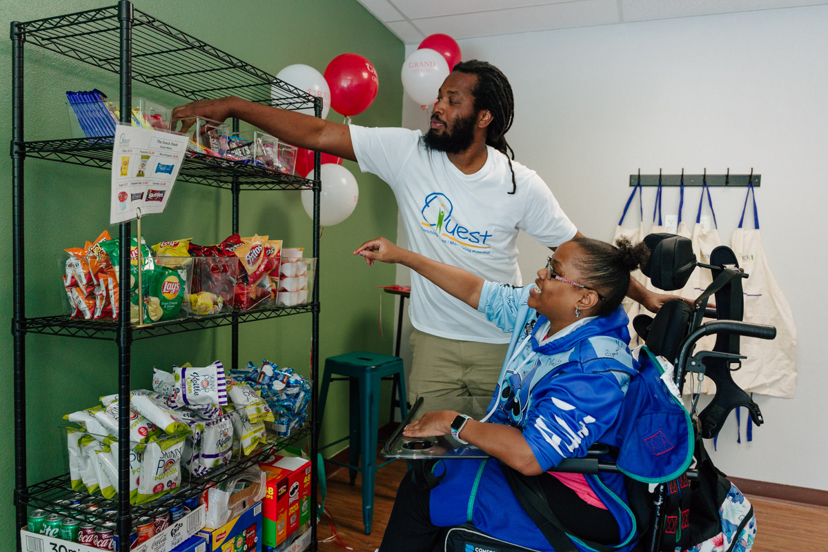 client with a quest staff member at the snack shack picking out an item.