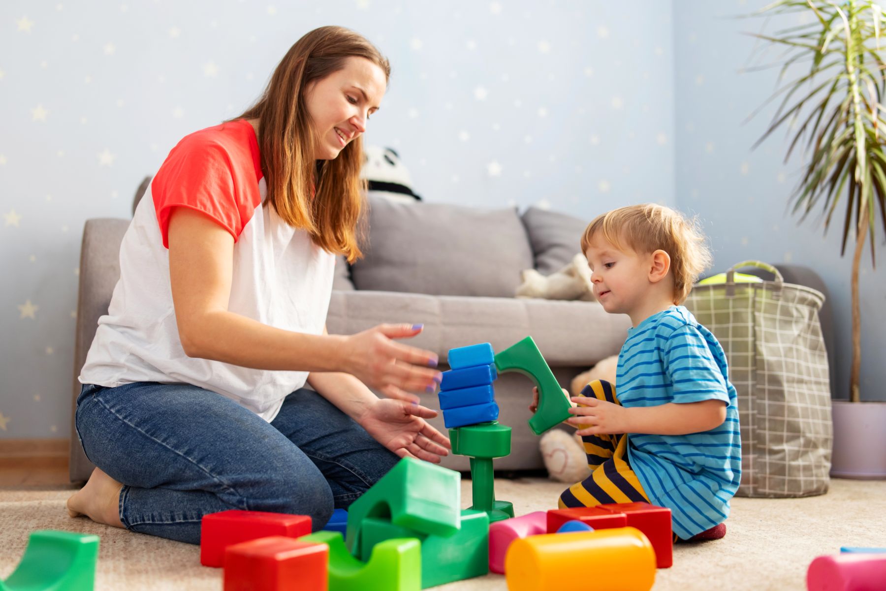 photo of woman with a child playing with blocks