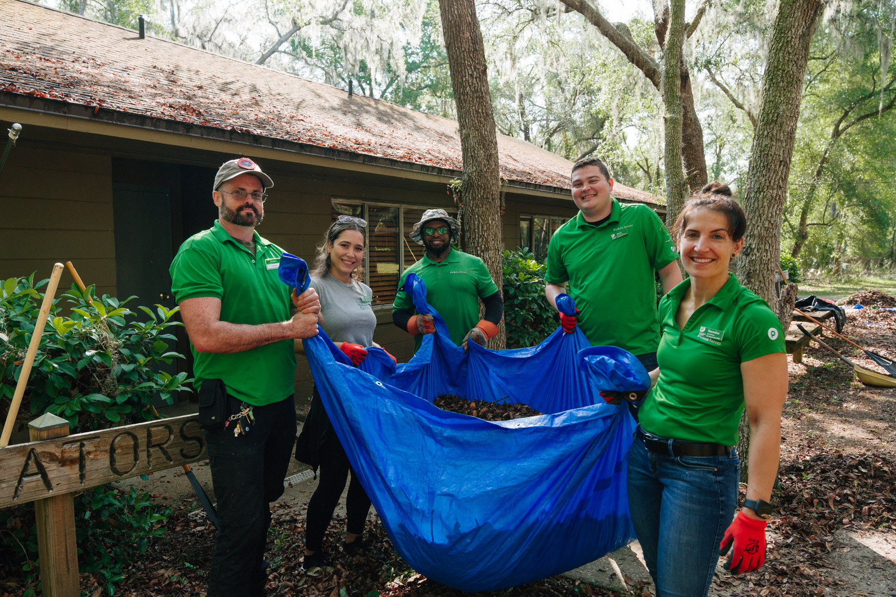 a group of Publix employees holding up a bag as they volunteer with Quest, Inc.