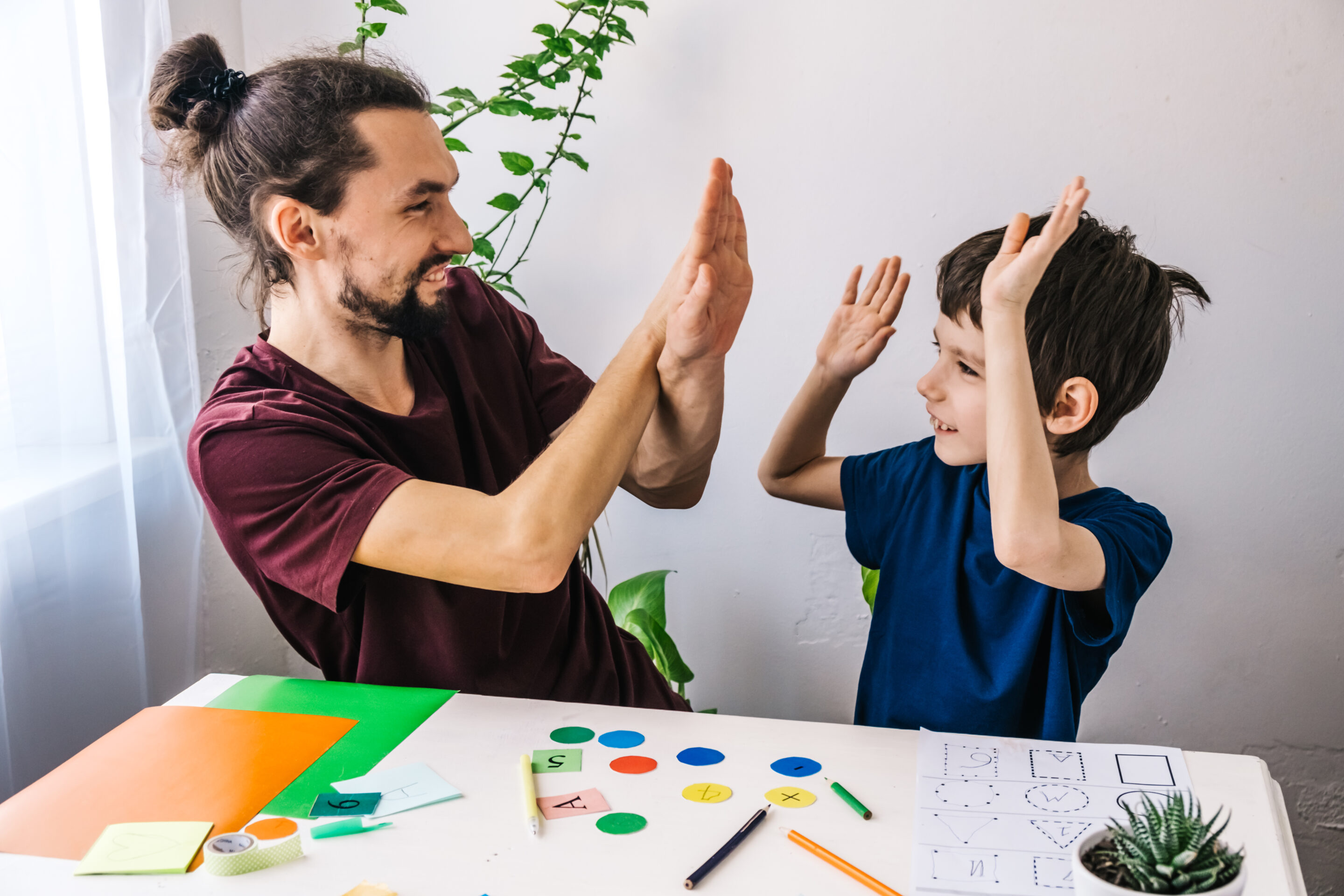 Happy autism boy during therapy with school tutor, early intervention