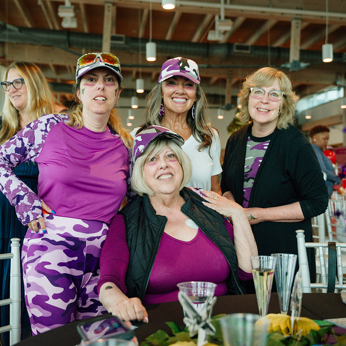 Man and woman holding up wine and spirits behind table at Wine Quest.
