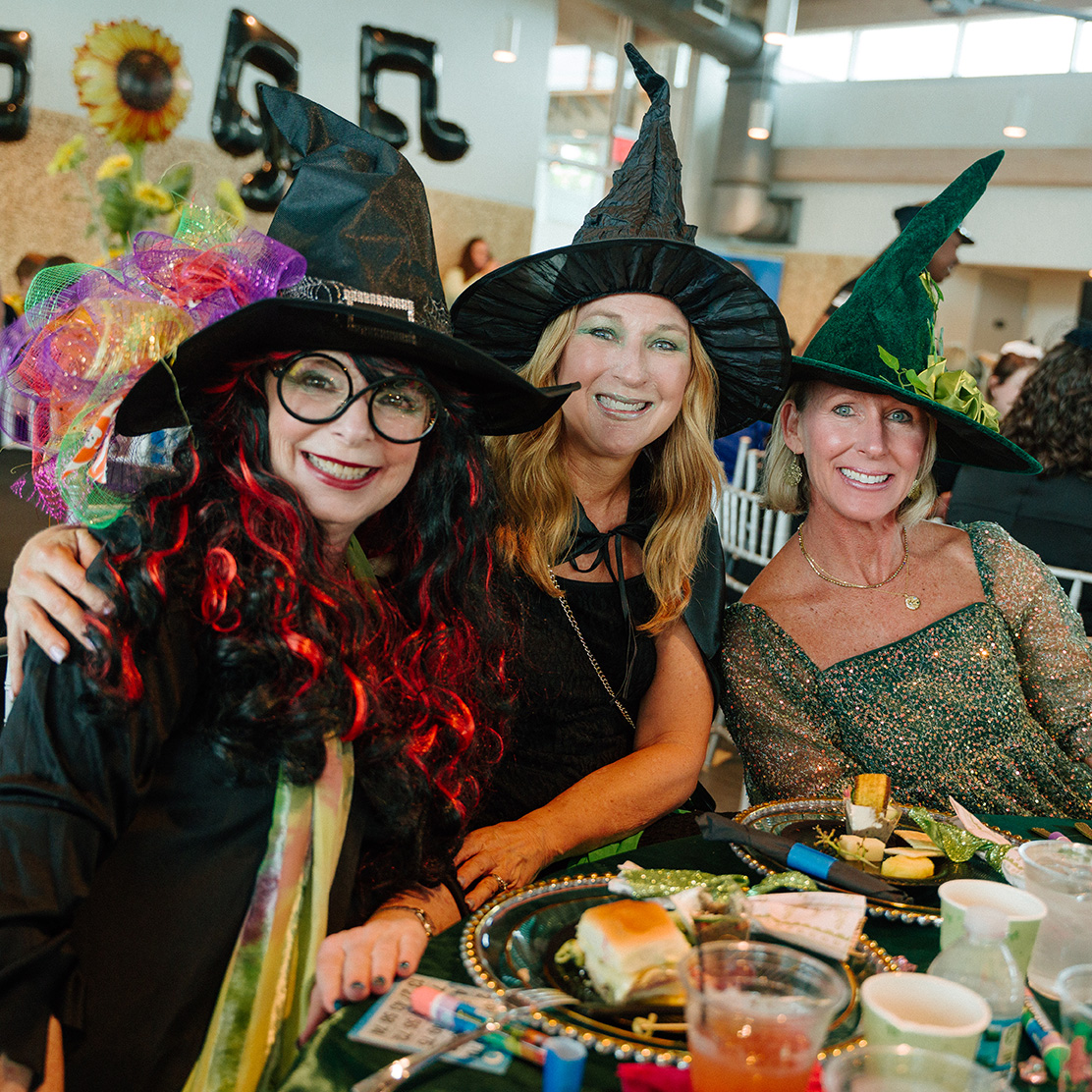 Man and woman holding up wine and spirits behind table at Wine Quest.