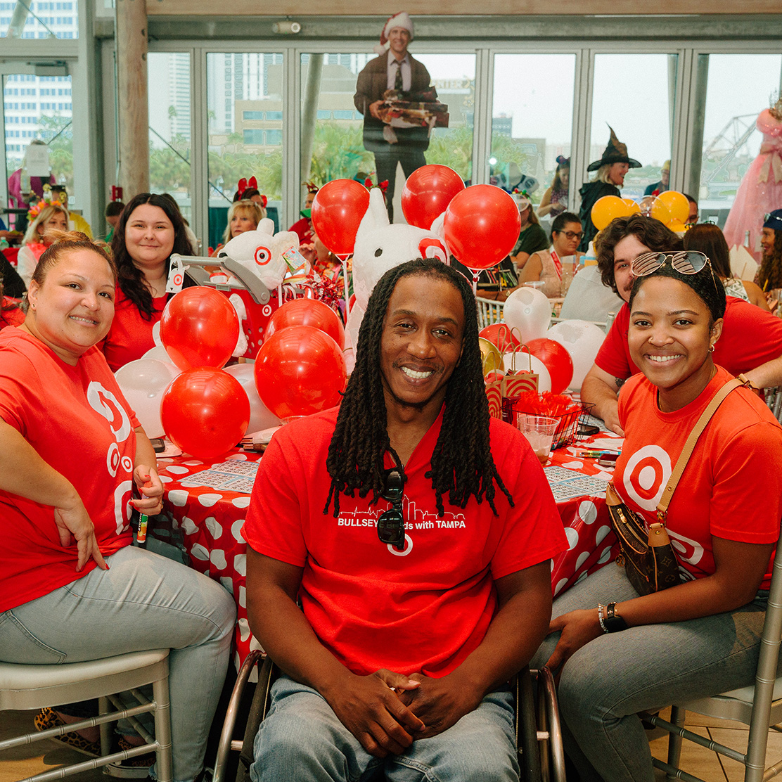 Man and woman holding up wine and spirits behind table at Wine Quest.